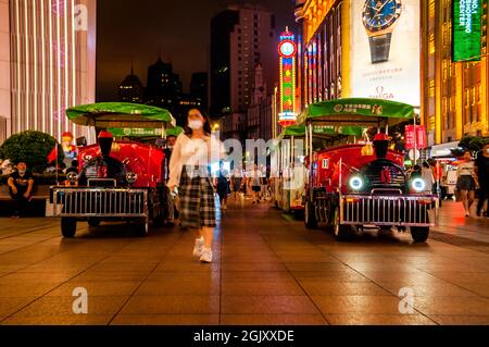 Fußgänger passieren nachts die Züge auf der Fußgängerzone der Nanjing East Road im Zentrum von Shanghai, China Stockfoto