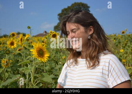 Glückliche, sorglose junge Frau im Spätsommer auf einem Sonnenblumenfeld Stockfoto