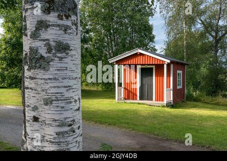 Anaset, Schweden - 08.22.2021: Außenansicht einer typischen schwedischen Holzhütte mit weißen Fenstern und Türrahmen. Camping in Schweden. Sommerurlaub und Stockfoto