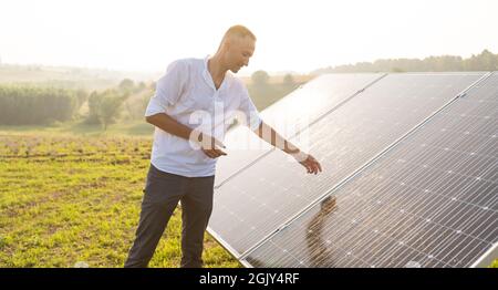 Der Ingenieur von oung überprüft den Betrieb der Sonne und die Sauberkeit der Photovoltaik-Solarzellen bei Sonnenuntergang. Konzept: Erneuerbare Energien, Technologie Stockfoto