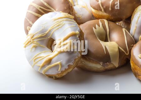 Köstliche Dougnuts stapeln mit Schokolade, Karamell und weißem Zuckerguss isoliert auf weißem Hintergrund mit Platz für Text Stockfoto