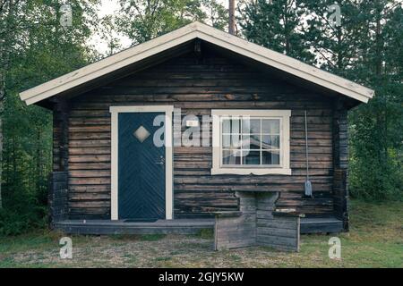 Anaset, Schweden - 08.22.2021: Außenansicht einer typischen schwedischen Holzhütte mit weißen Fenstern und Türrahmen. Camping in Schweden. Sommerurlaub und Reisen Stockfoto