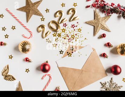 Offener brauner Umschlag mit weißer Blankokarte und verschiedenen Sternen mit den Zahlen von 2022 für das kommende Jahr Imitation von Explosion und festlichen saisonalen d