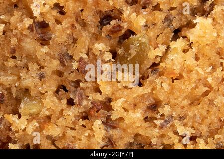 Flauschige Muffin- oder Kuchenstruktur, Makro. Backen oder gebacken gute Hintergrundtextur. Draufsicht auf feuchten und körnigen gelben bis goldbraunen gebackenen Muffin mit s Stockfoto