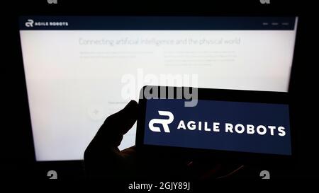 Person, die Smartphone mit Logo des deutschen Technologieunternehmens Agile Robots AG auf dem Bildschirm vor der Website hält. Konzentrieren Sie sich auf die Telefonanzeige. Stockfoto
