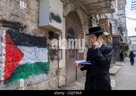 Ein orthodoxer Jude kommt an einer palästinensischen Flagge vorbei, die von extremen antizionistischen Haredi-Juden in Mea Shearim, einer ultra-orthodoxen Enklave in West-Jerusalem Israel, auf eine Wand gesprüht wurde Stockfoto