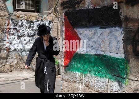 Ein orthodoxer Jude kommt an einer palästinensischen Flagge vorbei, die von extremen antizionistischen Haredi-Juden in Mea Shearim, einer ultra-orthodoxen Enklave in West-Jerusalem Israel, auf eine Wand gesprüht wurde Stockfoto