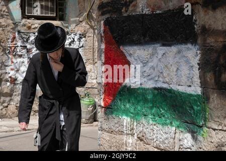 Ein orthodoxer Jude kommt an einer palästinensischen Flagge vorbei, die von extremen antizionistischen Haredi-Juden in Mea Shearim, einer ultra-orthodoxen Enklave in West-Jerusalem Israel, auf eine Wand gesprüht wurde Stockfoto