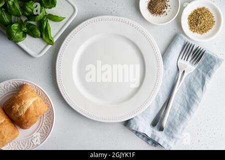 Leere weiße Platte. Brot, Salat, Gewürze, Geschirr auf hellem Hintergrund. Draufsicht, horizontal Stockfoto