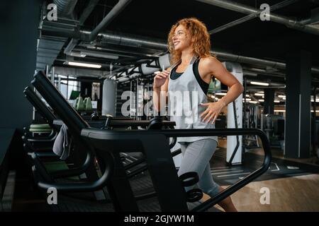 Die Frau, die auf dem Laufband im Fitnessstudio joggt, ist fit. Stockfoto