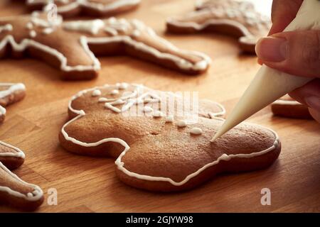 Handgemachte Lebkuchen Weihnachtskekse mit einem Kegel dekorieren - Zubereitung von traditionellem Gebäck Stockfoto