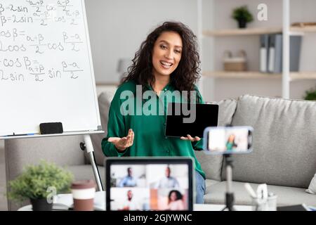 Lehrerin erklärt Mathematik online und zeigt Tablet auf Laptop Stockfoto