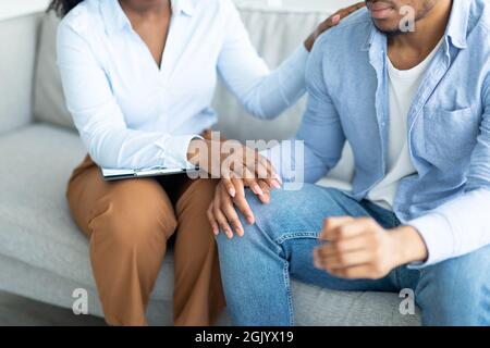 Unterstützung für Menschen mit psychischen Problemen. Psychologe hilft depressiven jungen Mann, berühren seine Hand im Büro Stockfoto