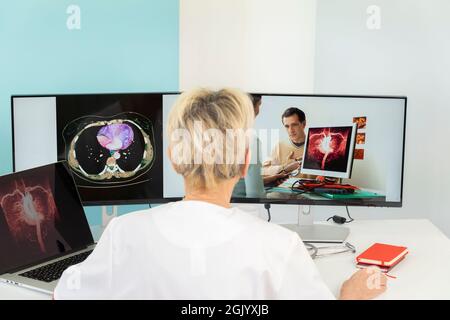 Telekonsultation zwischen zwei Ärzten mit medizinischen Bildern von Mägen auf einem der Bildschirme. Stockfoto