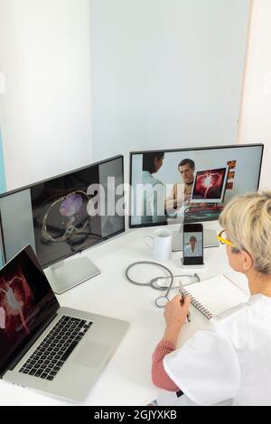 Telekonsultation zwischen zwei Ärzten mit medizinischen Bildern von Mägen auf einem der Bildschirme. Stockfoto