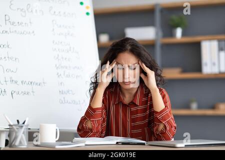 Gelangweilter und müder Lehrer berührt Tempel, die unter Kopfschmerzen leiden Stockfoto