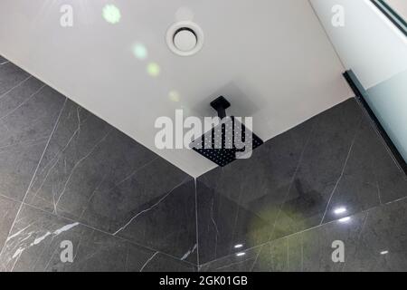 Nahaufnahme der Badezimmerdecke mit moderner Dusche und großen grünen Fliesen an den Wänden. Griechenland. Stockfoto