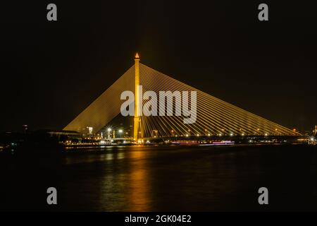 Rama VIII Brücke über den Chao Phraya Fluss, Bangkok, Thailand. Nächtliche Stadtszene, moderne Architektur, lange Beleuchtung. Konzept des Reisetransports Stockfoto