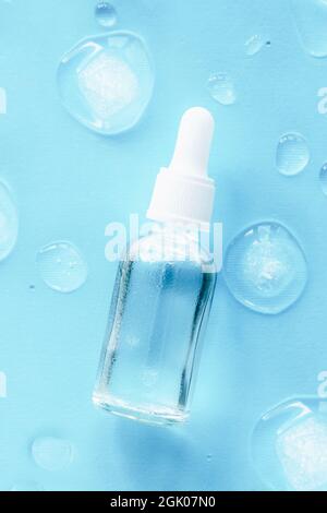 Feuchtigkeitsspendendes Serum in Glasflasche mit Tropf auf blauem Hintergrund. Draufsicht, flaches Lay, Mock Up. Stockfoto