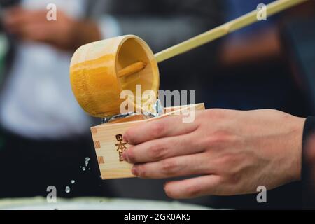 Braila, Rumänien - 26. August 2021: Details mit den Händen eines Mannes, der traditionellen japanischen Sake in einen Holzbecher gießt. Stockfoto