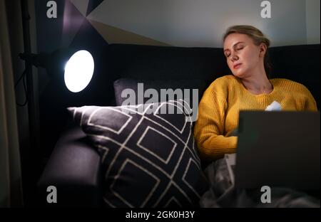 Müde Frau schlief ein, während sie versuchte, von zu Hause aus zu arbeiten. Stockfoto