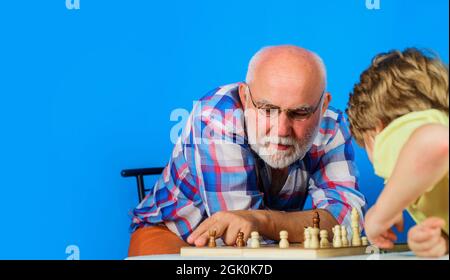 Schachspiel. Großvater und Enkel spielen gemeinsam Schach. Familienbeziehung mit Opa und Enkel. Speicherplatz kopieren. Stockfoto