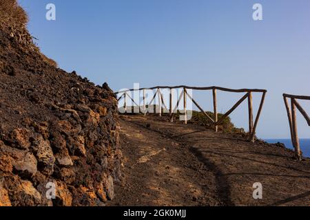 Weg zum Vulkan Monte Nero von Linosa. Charakteristische Landstraße mit der Trockensteinmauer, die aus Lavasteinen gebaut wurde Stockfoto