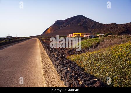 Straße mit Trockensteinmauer . Der Vulkan Monte Nero im Hintergrund. Linosa, Sizilien Stockfoto