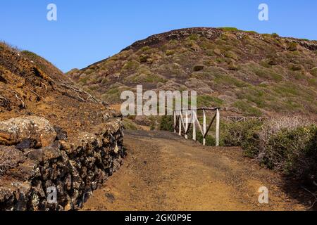 Weg zum Vulkan Monte Nero von Linosa. Charakteristische Landstraße mit der Trockensteinmauer, die aus Lavasteinen gebaut wurde Stockfoto