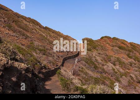 Weg zum Vulkan Monte Nero von Linosa. Charakteristische Landstraße mit der Trockensteinmauer, die aus Lavasteinen gebaut wurde Stockfoto