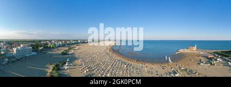 Caorle Beach - Panoramablick von oben während der Sommersaison auf die Wallfahrtskirche Madonna dell'Angelo am Meer. Stockfoto