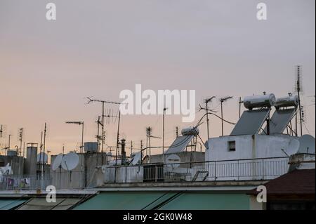 Stadtbild eines Wohngebiets in Athen bei Abendlicht. Stadtarchitektur. Sonnenkollektoren und Satellitenschüsseln auf dem Dach. Stockfoto