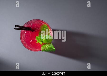 Nahaufnahme eines Cocktailgetränks mit roter Erdbeere und Minze im Glas auf grauem Hintergrund Stockfoto