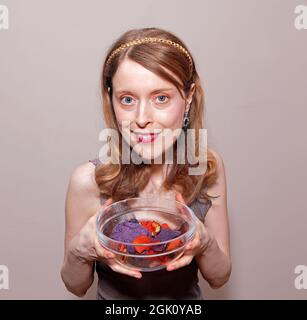 Junge hübsche Frau lächelt und hält Schüssel mit bunten Gemüsechips Stockfoto