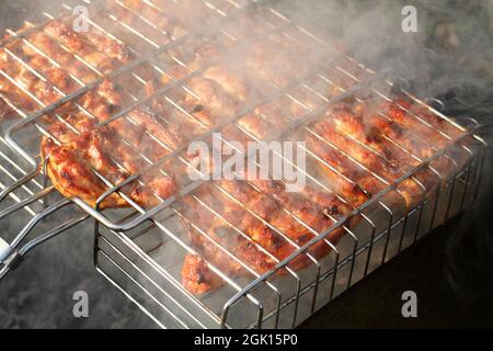 Hähnchenstücke, zwischen den Grillrosten gequetscht, auf einem Grillbräter braten. Nahaufnahme Stockfoto