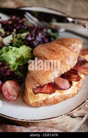 Gefülltes französisches Croissant mit Speck und Cheddar-Käse und Beilagensalat Stockfoto