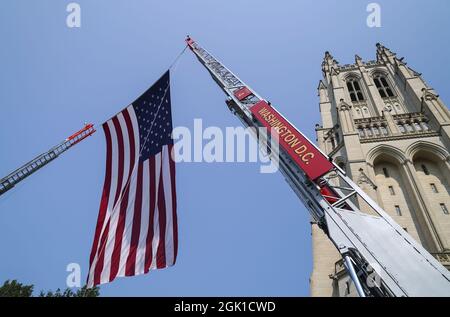 Washington, Usa. September 2021. Eine amerikanische Flagge hängt zwischen zwei Feuerwehrautos aus Washington, die zu Ehren der Feuerwehrleute geparkt wurden, die am 11. September 2001 in der Washington National Cathedral in Washington, DC, am Sonntag, dem 12. September 2021, ihr Leben verloren haben. Zum 20. Jahrestag der Anschläge vom 11. September wurde ein Gedenkgottesdienst abgehalten, um den bei den Anschlägen verstorbenen Ersthelfern zu gedenken. Foto von Leigh Vogel/UPI Credit: UPI/Alamy Live News Stockfoto