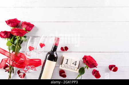 Liebe und Valentinstag Konzept aus Champagner Gläser, Wein, rote Herzen, Holzkalender und Rose auf weißem Holzhintergrund. Stockfoto