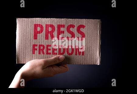 World Press Freedom Day Konzept. Hand hält Papppapier mit dem Text auf dunklem Hintergrund, konzeptuelles Bild, Symbol der Presse- oder Sprachfreiheit. Stockfoto