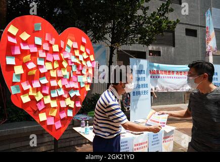 Hongkong, China. September 2021. Ein Mitglied der Organisation der Chiu Chow Gemeinschaft der Föderation von Hongkong übergibt einem Bürger während einer Massenkampagne auf einer Straße in Hongkong, Südchina, am 12. September 2021 Flugblätter. MIT "fast 1,000 Mitgliedern des Wahlausschusses, die sich auf der Straße befinden, um der öffentlichen Meinung in Hongkong Gehör zu schenken" Kredit: Li Gang/Xinhua/Alamy Live News Stockfoto