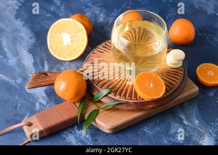 Glas mit leckerem Getränk, Pillen und Zitrusfrüchten auf farbigem Hintergrund Stockfoto