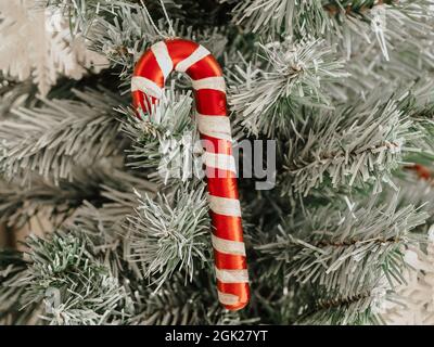 Weihnachten Hintergrund. Zuckerrohr, rot-weiß gestreifte Dekoration auf Tannenbaum bedeckt, weißer Schnee, Nahaufnahme. Stockfoto