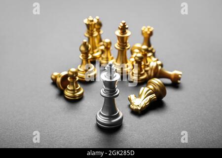 Silberner König zwischen goldenen Schachfiguren auf grauem Hintergrund Stockfoto