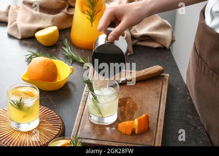 Frau goss Saft in Glas auf dem Tisch in der Küche Stockfoto