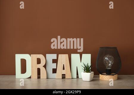 Stilvolle Lampe mit Dekor auf dem Tisch vor farbigem Hintergrund Stockfoto