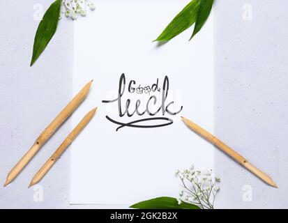 Papier mit Text GOOD LUCK, Dip Stifte und Blumen auf weißem Hintergrund Stockfoto