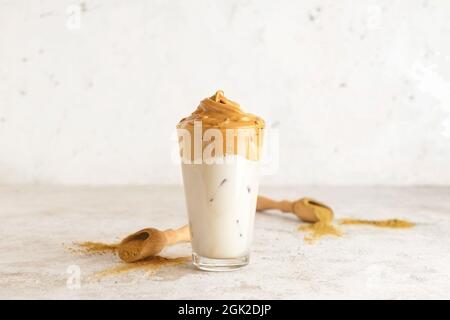 Ein Glas leckeren dalgona hojicha Latte und Pulver auf hellem Hintergrund Stockfoto