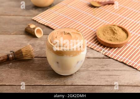 Ein Glas schmackhaften dalgona hojicha Latte auf einem hölzernen Hintergrund Stockfoto