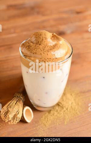 Glas schmackhaften dalgona hojicha, chasen und Pulver auf hölzernen Hintergrund Stockfoto