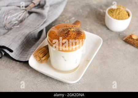 Ein Glas leckeren dalgona hojicha Latte und Chasen auf grunge Hintergrund Stockfoto